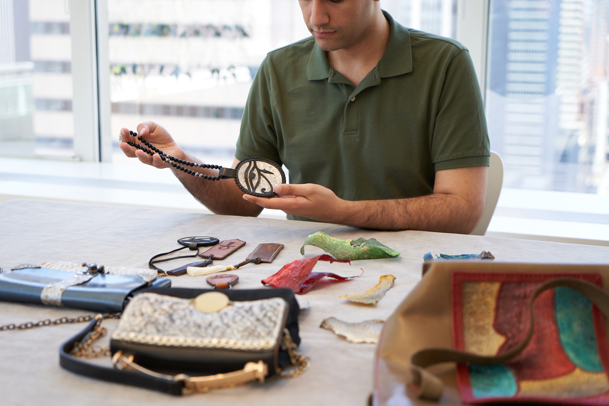Visenleer founder examining small accessories and material samples